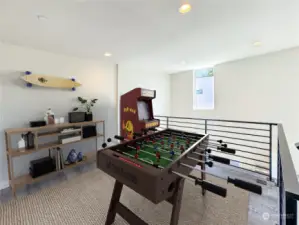 This truly is a versatile floor! This concept features a stylish game room with a foosball table, Pac-Man arcade machine, and modern decor for entertainment.