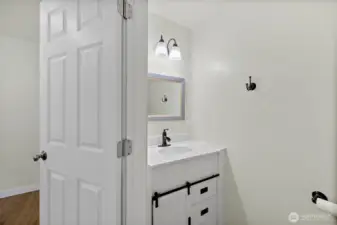 Half bath with updated vanity, bronze fixtures, and a framed mirror for a polished touch.  Located in the primary ensuite.