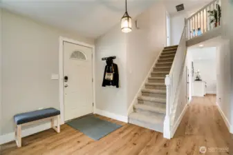 Now that we've seen a preview of the main floor, let's start at the beginning and see it all. The front door opens from the covered front porch to this entry area. The open staircase leads up to a full bath and the 3 bedrooms, including the primary suite. But for now, start with a visit to the living room.