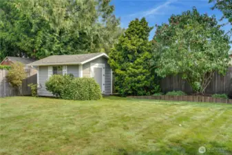 A well-tended garden shed stands in the back corner of the yard.