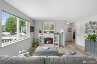 The living room features a large window for an abundance of natural light. The hallway leads to 2 bedrooms and a bathroom.