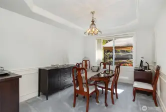 The living area seamlessly flows into the dining room with tray ceilings, creating an open and connected space.