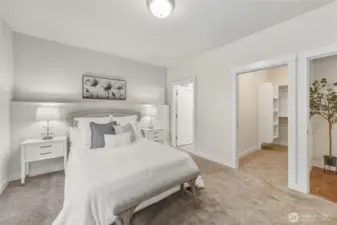 Another view of the primary bedroom with a view of the walk in closet and attached bathroom.