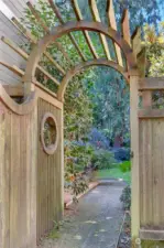 Charming gate with trellis and pathway to backyard.