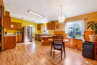 A view of the kitchen and dining room from the family room. Beyond the fridge is the laundry room and primary bath as well as the back door.