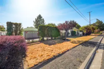 To the left of the home is a driveway, shrubbery, garage, and a lattice wall that has some stainless glass installed for privacy of the driveway.