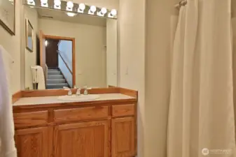 Lower level Full Bath is located at the base of the stairs across from the Laundry Room. You can see the stairs to the entry way in the mirror.