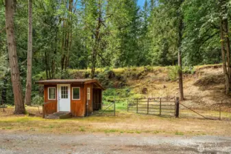 Partially fenced acreage with outbuilding, previously used for goat house.