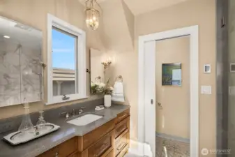 Spa like primary bathroom with marble floors, quartz counters, gorgeous hardwood vanity and radiant heat floors.