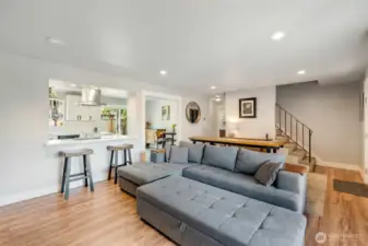 Open space between eat in kitchen and living room through wide door frame and half wall.