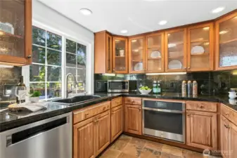 Stainless steel appliances, granite tile counters, glass-front cabinets, and under-cabinet lighting in this well equipped kitchen. Large window and solar tube add natural light.