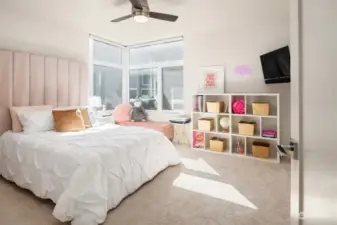 A large secondary bedroom houses a queen bed, cabinets and a desk, as well as a closet outfitted by California Closets.