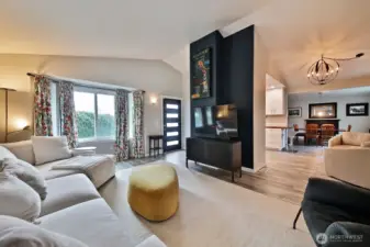 Looking back at the front entrance and bay window (east side of your home), your first glimpse of the kitchen (behind the accent wall with the tv stand) and the dining room off in the distance.