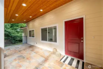 There is a large tiled front porch sitting area at the front entry which is surrounded by evergreens.
