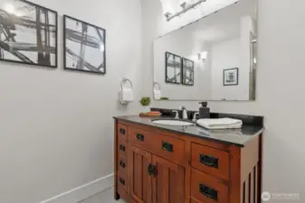 This main-level bathroom features a rich wood vanity with granite countertops, sleek fixtures, and stylish finishes.