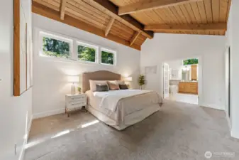 The expansive Primary Suite features stunning wood-planked ceilings, wall to wall carpet, elevated windows for natural light, and a seamless connection to the spa-inspired ensuite.