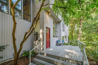 Inviting front deck provides a quiet spot to take in the surrounding greenery, framed by timeless architectural details and natural charm.
