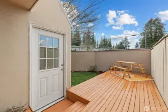 The deck leads to grassy space and garden area.