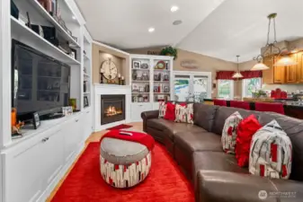 The open concept kitchen family area with it cozy gas fireplace, beautiful cabinets and vaulted ceilings beacons you to sit down and stay awhile.