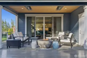 The covered patio features a fire pit and ceiling-mounted heater, offering year-round comfort for outdoor gatherings. This stylish space combines warmth, ambiance, and fresh air, making it perfect for entertaining or relaxing in any season.