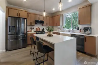 Completely renovated kitchen with quartz waterfall island. Please note cabinetry is a muted beigey brown, the lighting changed the hue a bit. It is so beautiful in person