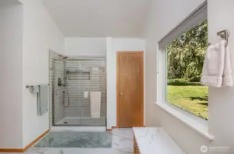 Recently renovated en-suite primary bath features walk-in shower, large window, and closet for all your bathroom necessities.