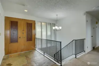 Wood Double Doors lead you into a natural stone entryway to the main part of the home. Stairs leading down to the Lower Level.