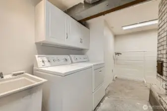 Large laundry room with sink and storage. Concrete floors.