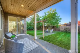 Covered porch with brick pavers leading to outdoor fire bowl.