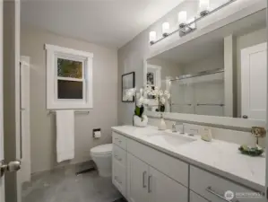 The second story guest bathroom features a tub/shower, quartz countertops, shaker-style cabinets, and tile flooring.