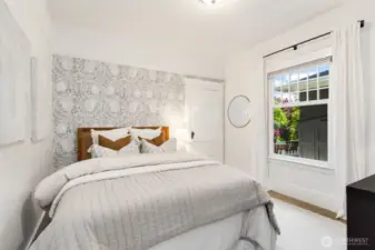 The main floor bedroom features beautiful wallpaper accent and a window to the side yard.  The door goes to a large walk-in closet.