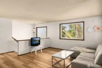 Bright and inviting living space with warm luxury vinyl plank floors, abundant natural light, and serene treetop views—ready for your personal touch.