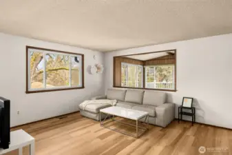 Sunlit living room with durable luxury vinyl plank flooring, expansive windows, and seamless flow to a cozy sitting area—perfect for everyday living and easy entertaining.