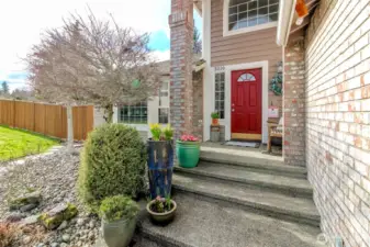 Beautiful timeless brick entry with brick-wrapped columns, large windows, and a welcoming covered porch.