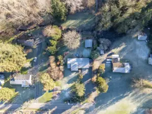 An aerial view of the property where you can see the chicken coop and garden space in front, and the large shed in the rear yard behind the house.