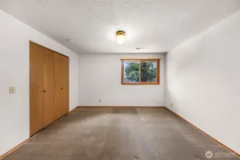A lower-level bedroom offers a quiet retreat with a spacious layout, double-door closet, and garden-facing window for tranquil views.