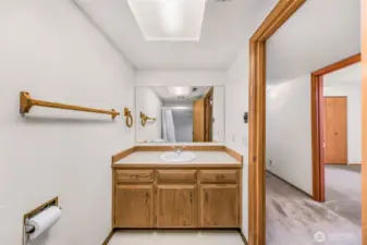 The downstairs full bath features a single sink vanity, large wall mirror, and bright overhead lighting. Oak cabinetry and neutral tones complete the functional space.