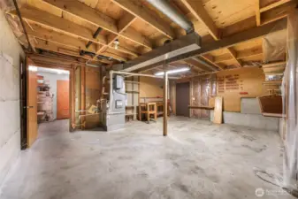 The unfinished utility area includes workspace, exposed beams, furnace, and extensive shelving—ideal for projects, storage, or a workshop.