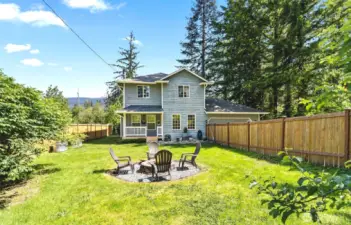 Closer view of fenced front yard with fire pit.