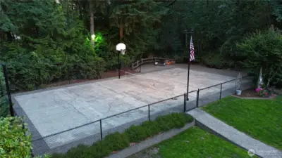 Drone Shot Sports Court, w/ Fire Pit right above the rippling year round creed in the greenbelt beyond.