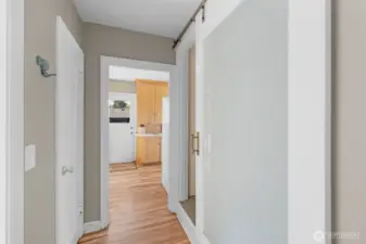 The main floor hallway between the primary bedroom, bath and kitchen area is light & bright and flows easily in this circular floor plan.