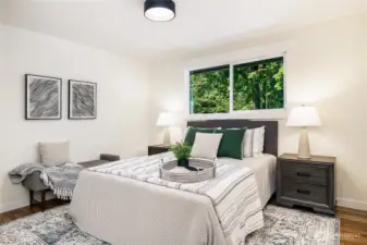Spacious primary bedroom with a window overlooking the back yard and deck. En-suite bath located just to the right, just out of frame