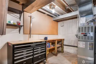 Downstairs furnace room has a shop area with built-in work bench, peg board, and shelving. To the right of the furnace there is even more space for storage. The furnace is made by Trane who is well known for making high-quality, long-lasting equipment.