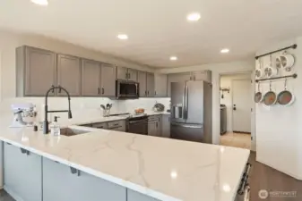 Captivating kitchen boasts sublime quartz counters, recessed lighting, and appliance suite--who wouldn't enjoy spending time here??