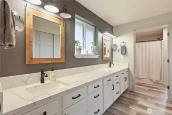 Quartz counters grace this extra long vanity with dual sinks, privacy window brings in natural light, LVP floors and additional closet (seen in mirror) offer style and convenience.