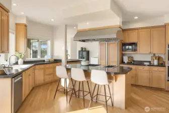 A culinary masterpiece featuring a massive center island, a professional Wolf six-burner cooktop, and a sleek Thermador hood. Check out all of that natural light showering the home!