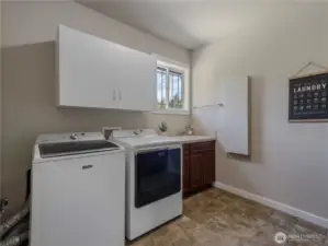 Upper level laundry room with storage cabinets, utility sink and built-in ironing board.