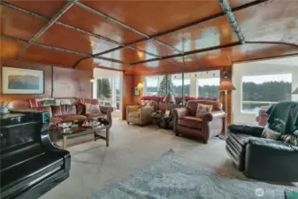 Warm and inviting living room with rich wood ceilings and expansive water views.