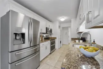 Granite counters, sleek stainless steel appliances, and classic tile flooring create a stylish, cohesive kitchen space.