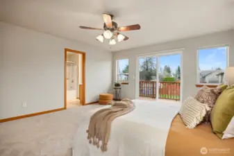Looking across the primary bedroom toward the full bath and glass sliding door that leads out to the back deck.